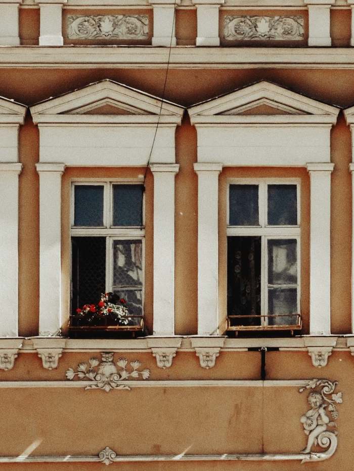 Altbaufassade mit Stuck, hellen Fensterrahmen und warmem Anstrich — Beispielfoto